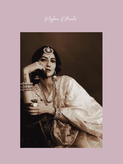 A portrait exuding vintage charm. The bride's pose and the warm tones of the photo complement her classic white saree and traditional maang tikka, creating a look that feels like a treasured heirloom.