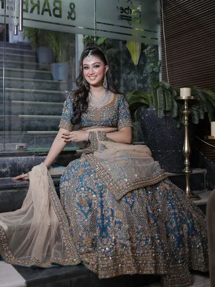 The full look, with the bride posing on the stairs of our salon. The teal lehenga is absolutely breathtaking.