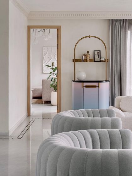 A view of the living room showing the custom gradient bar and sinuous grey armchairs. The design explores the use of gold in a delicate, alluring way without being flashy.