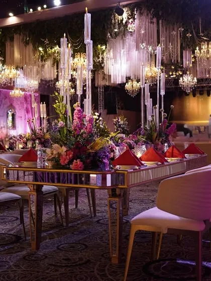 A wider view of the dining area, showing the long mirrored table and the magnificent ceiling treatment with hanging greenery and countless crystal chandeliers.