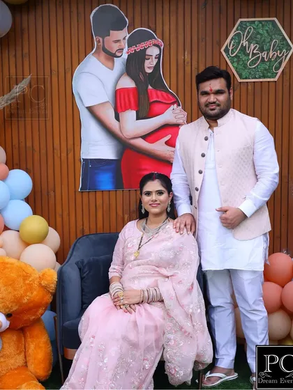 The happy couple posing at their teddy bear themed baby shower. The personalized backdrop and balloon decor create a joyful and memorable setting for their celebration.