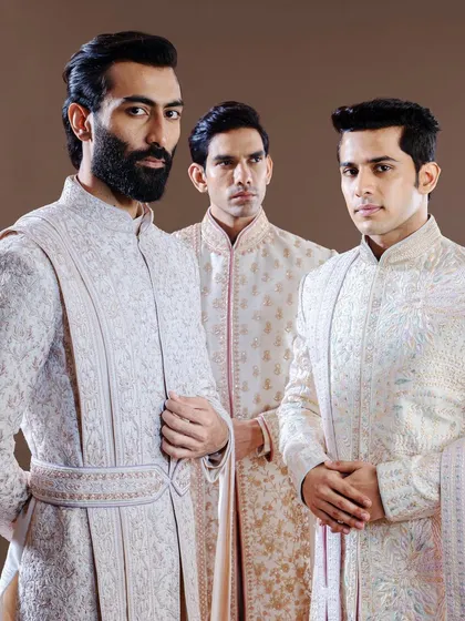 Three distinct personalities, one standard of excellence. This image displays the variety within our sherwani collection, from subtle textures to more pronounced embroidery, catering to the unique style of every groom and groomsman.