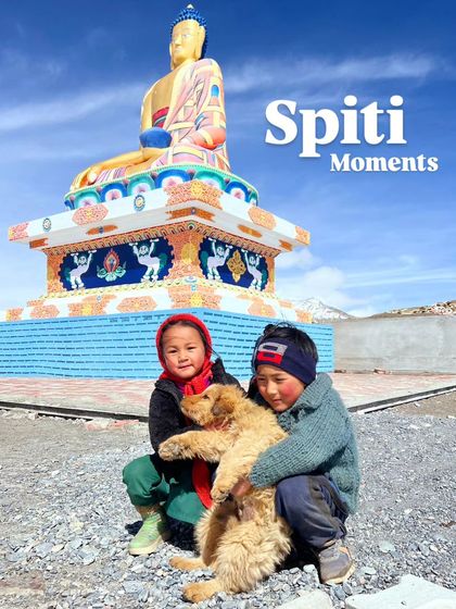 Two local children with a dog in front of the Langza Buddha statue, a heartwarming moment.