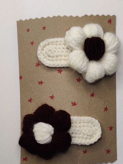 A pair of aesthetic, minimalist hair clips in brown and white with a puff flower design.