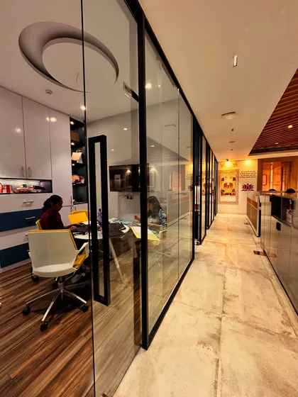 Transparency and connection are key in a modern office. Here, glass partitions for private cabins create a sense of openness, allowing natural light to flow through the space while maintaining a clear view of the office's central design narrative.