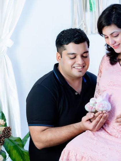 The tiny baby shoes are a perfect prop to symbolize the little one on the way. This couple shares a smile while holding the shoes near the baby bump.