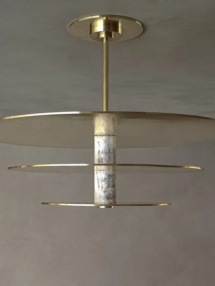 A detailed view of our custom ceiling light, where we explored the interplay between materials. The fixture combines cool, veined marble with the warmth of spun brass discs, creating a sculptural centerpiece for an entrance foyer.