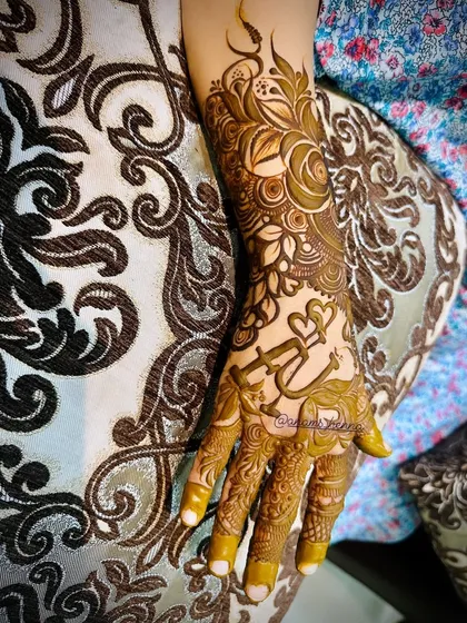 The finished look of a custom henna piece featuring the initial 'A' and interlocking hearts. This is a romantic design that’s very popular with my clients.