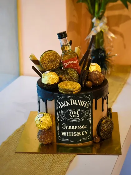 For the whiskey lover, this Jack Daniel's themed cake is the perfect treat. It features a rich chocolate drip, a miniature bottle of JD, and is loaded with Ferrero Rocher chocolates and gold-dusted macarons.