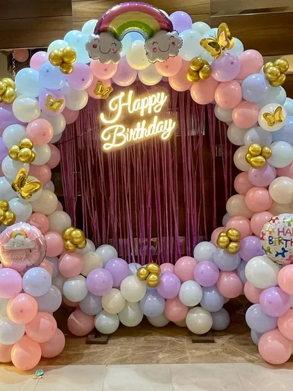 A beautiful pastel-colored balloon ring with a 'Happy Birthday' neon sign and a purple fringe curtain, perfect for a unicorn or princess party.