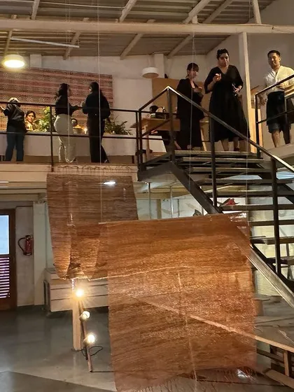 The team celebrating the conclusion of our 'Cu+Fibers 2024' exhibition in our studio. The space is filled with our large-scale woven sculptures, creating a backdrop for the gathering.