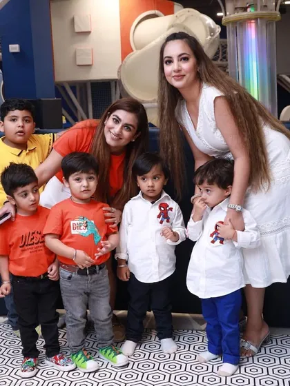 A group of kids and their moms posing for a picture in the play area. It's a place for both kids and adults to enjoy.
