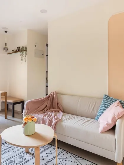 A cozy living room designed on a budget, featuring a comfortable sofa, a corner gallery wall, and a compact dining nook by the window.