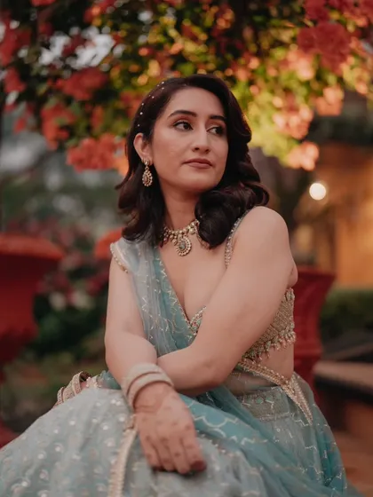 A beautiful portrait of the bride sitting amidst lush greenery, her thoughtful expression captured in the soft evening light.