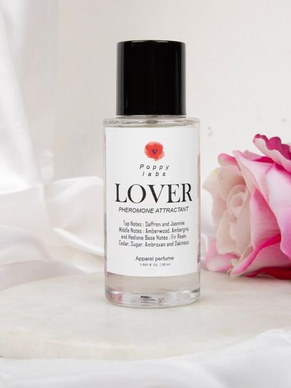 The 'Lover' perfume bottle placed on a white marble coaster against a delicate white fabric, creating a clean, high-end aesthetic for beauty product photography.