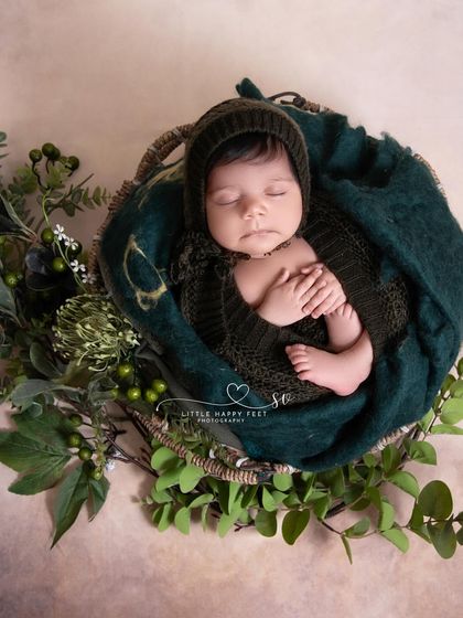 Wrapped in deep green and nestled in a basket of leaves. The rich, dark colors create a cozy and womb-like environment.