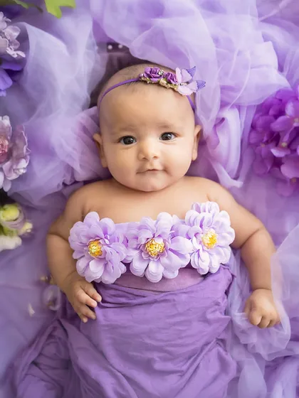 A garden of dreams. This baby girl, surrounded by a sea of purple tulle and flowers, looks like a tiny fairy.