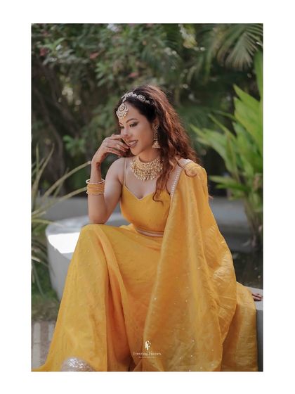 A beautiful solo portrait of the bride, smiling shyly in her yellow Haldi lehenga. A quiet moment amidst the joyful celebrations.