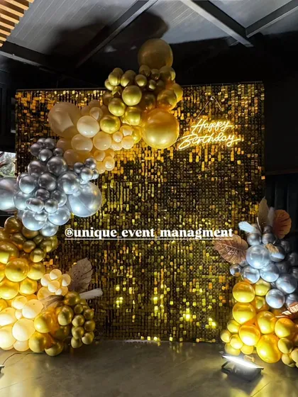 For a milestone celebration, we put together this glamorous photo booth. It features a shimmering gold sequin wall, a custom 'Happy Birthday' neon sign, and organic balloon garlands in gold and silver, creating a perfect spot for memorable photos.