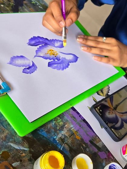 A student practicing the one-stroke painting technique to create beautiful, blended flower petals with a single brush movement.