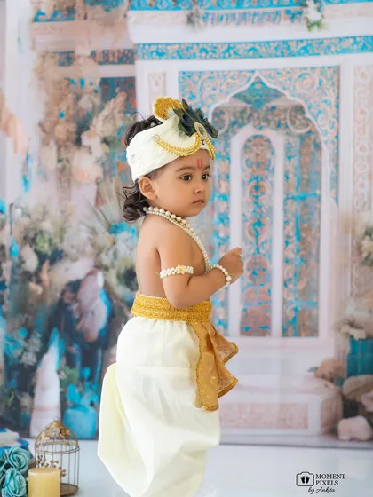 A side profile of our little Krishna. This shot highlights the beautiful details of his costume and the serene expression on his face.