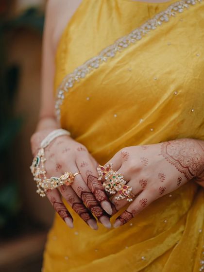 A close-up detail shot of the bride's hands, adorned with beautiful henna and traditional floral jewelry.