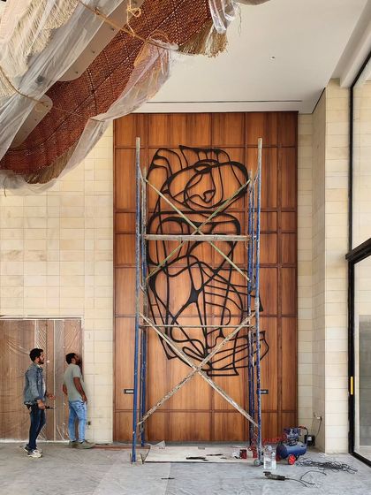 This image captures the installation process of a large-scale abstract line art piece on a towering wooden wall. It demonstrates our approach to integrating bold metal sculptures into architectural surfaces, creating a focal point that is both raw and refined.