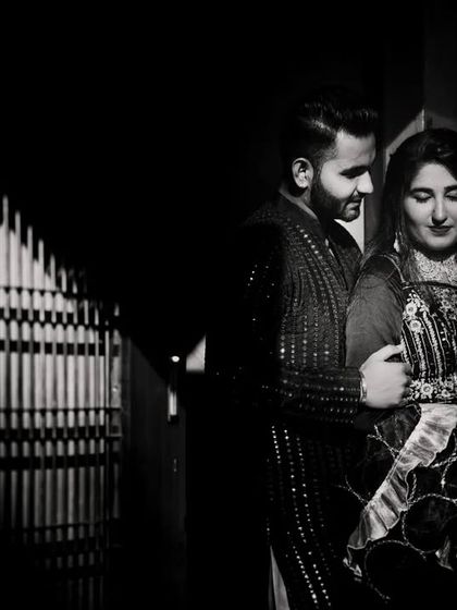 An intimate black and white portrait of the couple in a low-light setting. The shadows create a sense of privacy and romance.