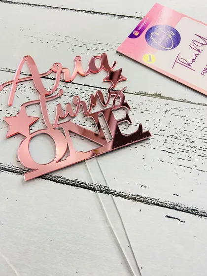 Here is the "Aria Turns ONE" topper in rose gold, laid flat to show the precise cut and design details before it goes on the cake.