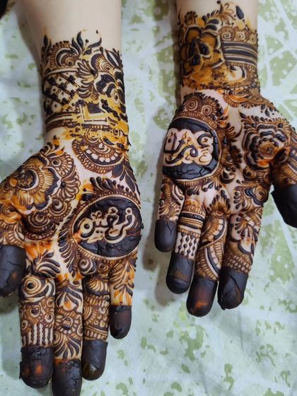 This design features names written in beautiful Arabic calligraphy on both palms, making it a centerpiece of the intricate mehendi.