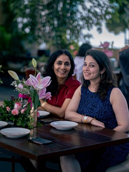 Two guests smile for the camera, enjoying the floral decorations and warm atmosphere of our event.