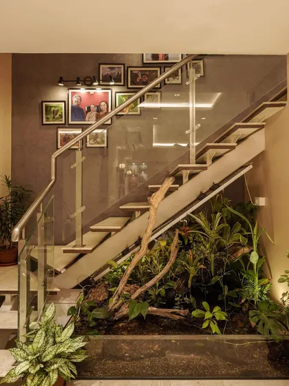 A modern staircase with a glass railing and a unique under-stair garden, blending nature with contemporary design.