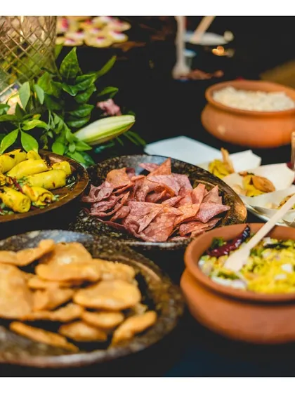 A rustic and earthy spread of traditional Indian snacks, including khandvi, chakli, and poha, served in terracotta and stone bowls. This buffet setup celebrates the rich and diverse flavours of regional Indian cuisine.
