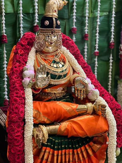 This Varamahalakshmi idol is draped in a vibrant orange and green silk saree, colors that represent auspiciousness and new beginnings.