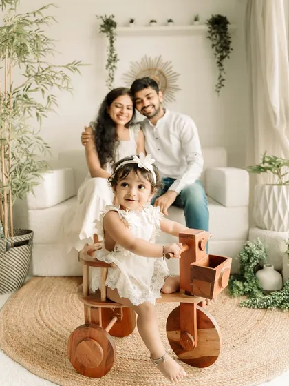 A lovely family portrait with their one-year-old daughter taking center stage on her wooden tricycle.