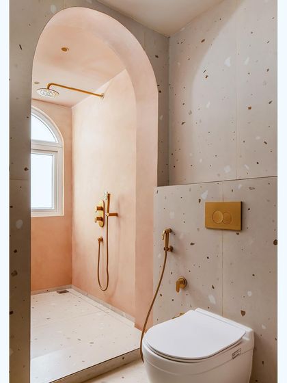 The daughter's bathroom features a playful mix of terrazzo, microcement, and peach-colored walls, with an arched shower area.