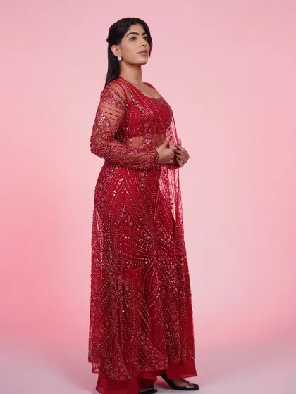 A side view of the red three-piece Indo-Western set, highlighting the sheer, sparkling jacket and the flattering wide-leg pants.