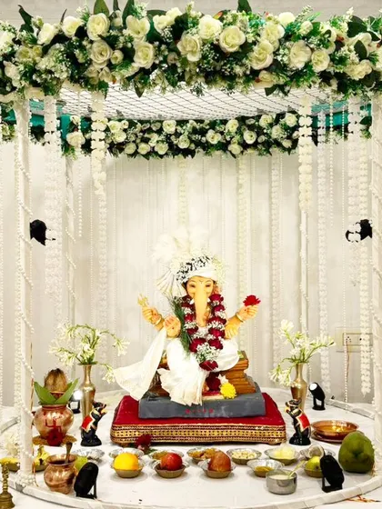 This minimalist design features a four-poster canopy draped with strings of white pearls and flowers. The all-white theme creates a peaceful and divine setting for the Ganpati idol.