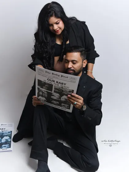 This candid-style shot captures the couple sharing a moment while reading their special "Baby Post" newspaper. It’s these unposed, interactive moments that often become the most cherished photographs.