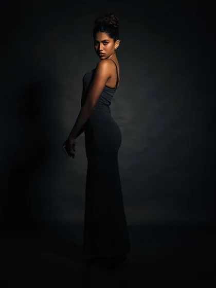 A study in shadow. The light is used sparingly to carve the model's silhouette out of the darkness, creating a mysterious and elegant image.