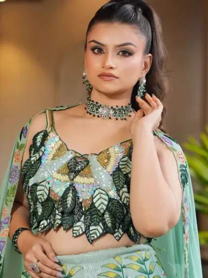 A close-up view of the delicate craftsmanship on the pastel green lehenga's blouse and the matching jewellery.