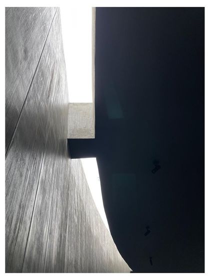 An abstract detail of the curved concrete walls, showing the play of light and shadow on the raw material.