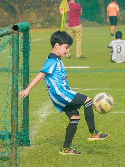 A young player practices his ball-juggling skills by the goalpost, a great way to improve touch and control.