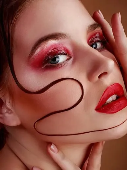A close-up showcasing textural effects in makeup. I paired a vibrant red smokey eye and matching lip with a sleek, graphic gel swirl on the face for a unique and artistic finish.