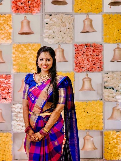 My bride looking radiant against a colorful backdrop of flowers and temple bells. The multi-colored saree is complemented by a classic makeup look.