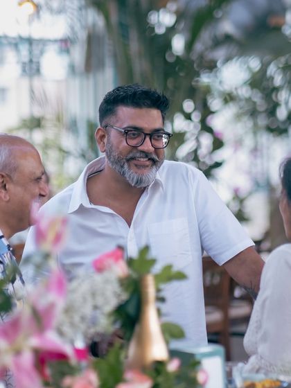 A candid shot of a guest in conversation, surrounded by the beautiful floral arrangements of our Golden Circle event.