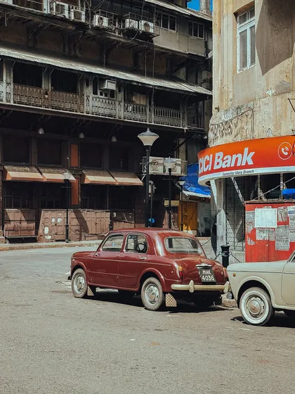 A vintage Fiat car parked on a quiet side street, showcasing the everyday, lived-in history of Bombay.