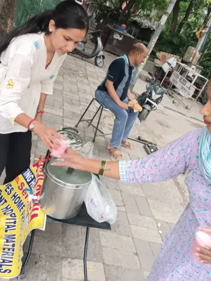 A volunteer hands a glass of Chabeel to a woman on the street. These small interactions are what build a compassionate community, one glass at a time.