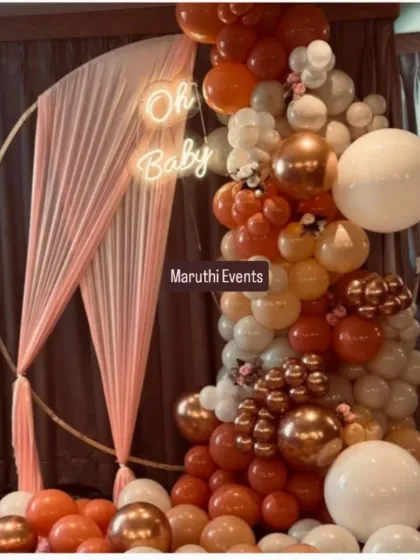 A chic and modern "Oh Baby" shower with a boho feel. The circular gold frame is draped with fabric and a stunning organic balloon garland in rust, peach, and white tones.