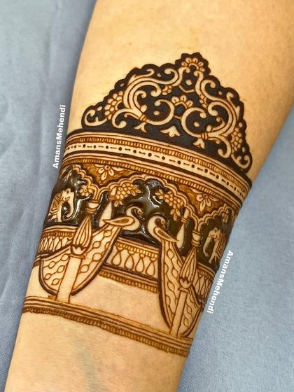 A close-up of the top part of the arm band, showing the beautiful details of the peacocks and elephants in a palace setting.